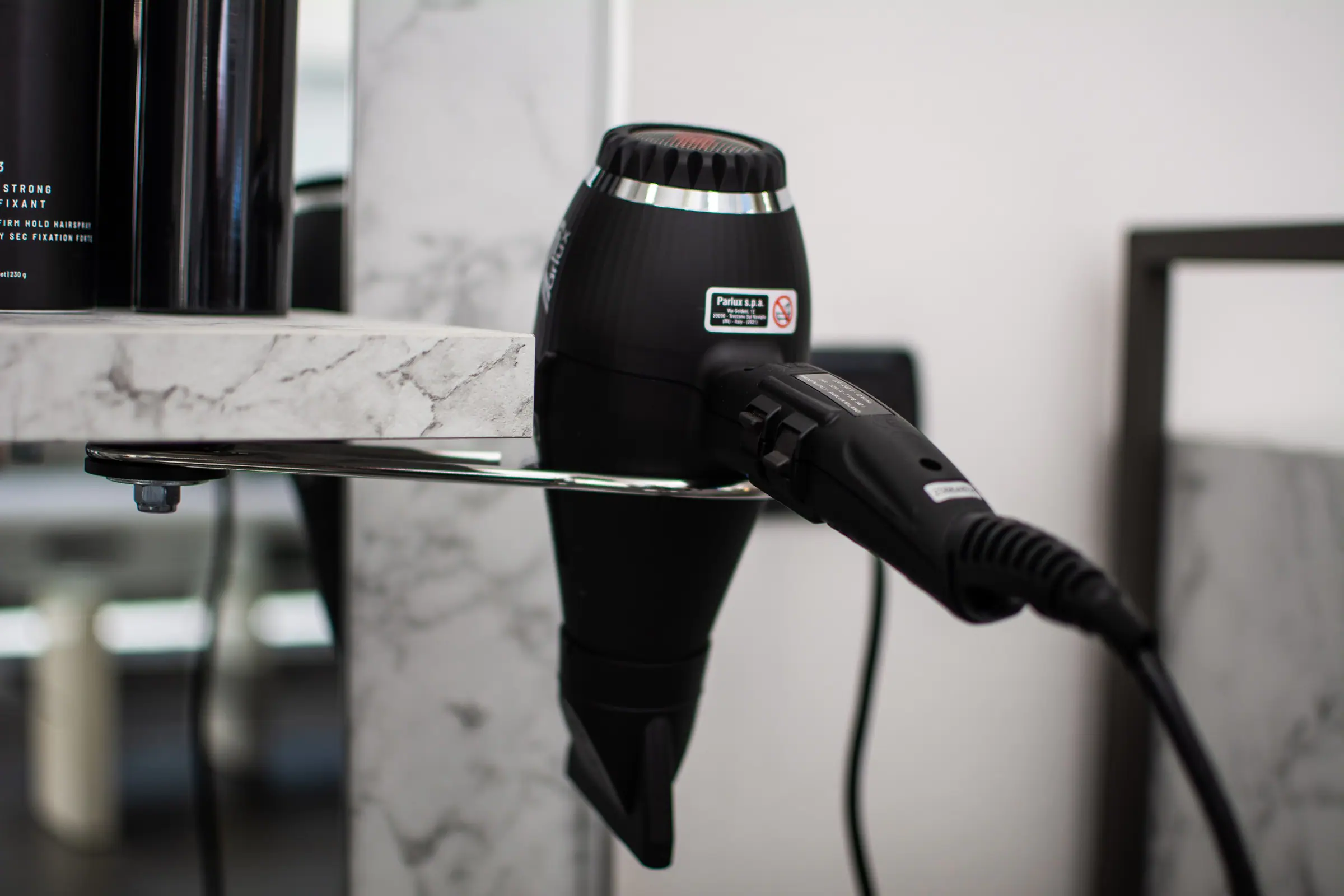 Asciugacapelli nero appoggiato a una mensola di marmo in postazione